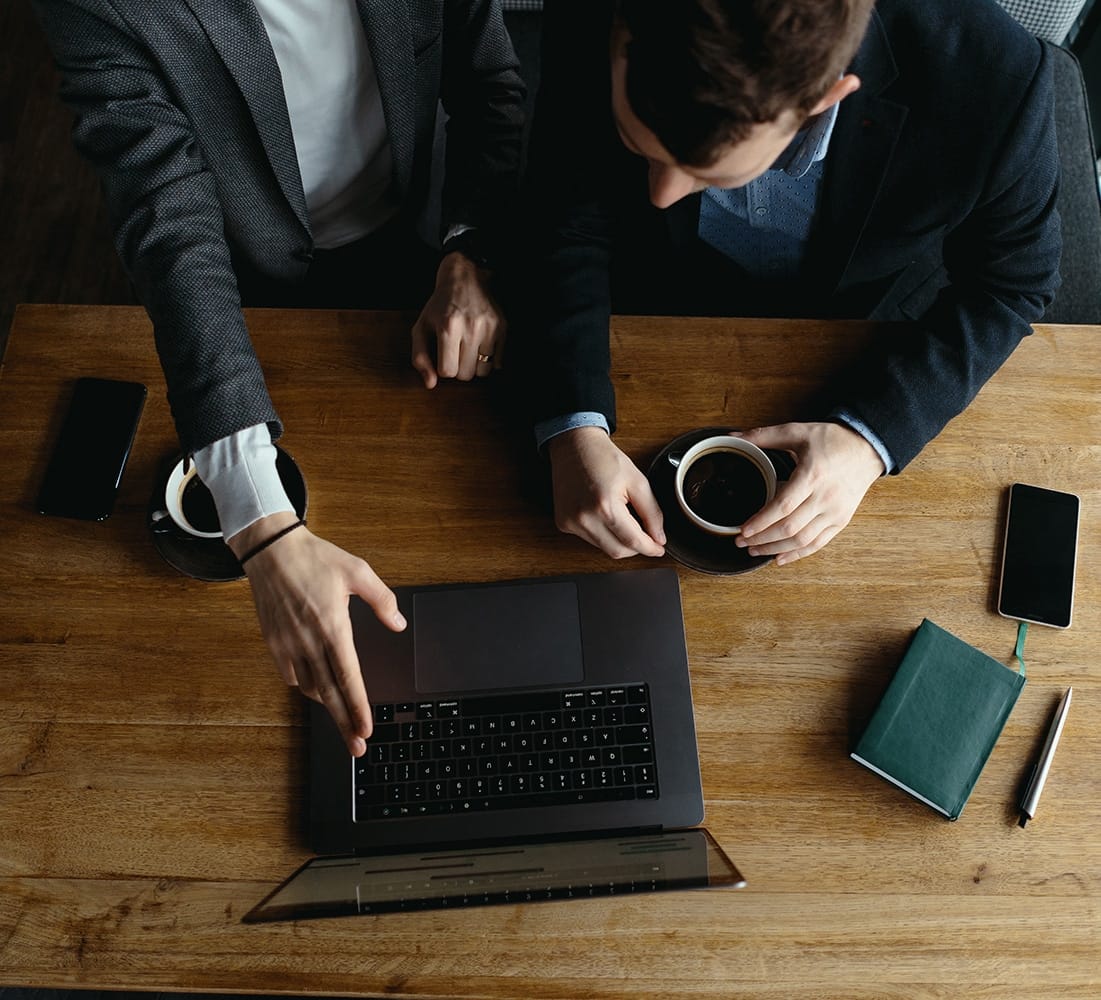Two businessmen pointing laptop screen while discussing Two handsome businessmen are talking and pointing laptop screen while discussing. Business. Technology. Partnership.